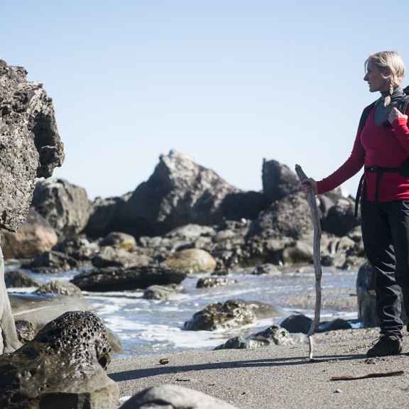 Person with tramping stick on beach